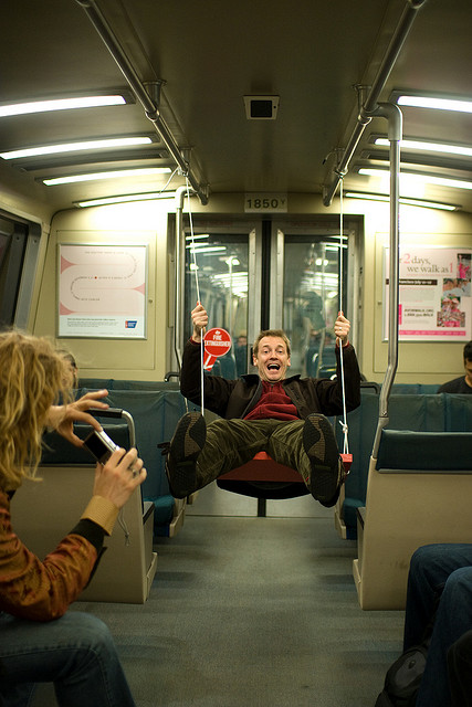 A man swings through the aisle of a train.